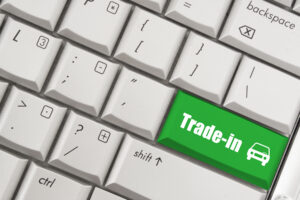 Close-up of a keyboard with a green key labeled “Trade-in” and a car icon, symbolizing online vehicle exchange