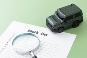 SUV car and magnifying glass on a blank checklist form, symbolizing vehicle inspection or car buying preparation