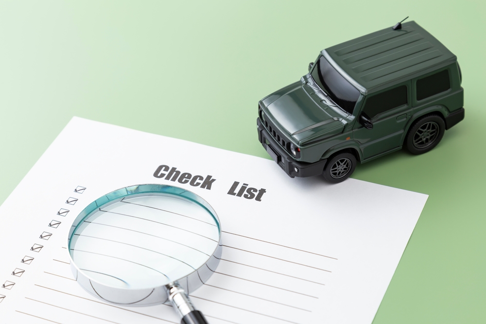 SUV car and magnifying glass on a blank checklist form, symbolizing vehicle inspection or car buying preparation